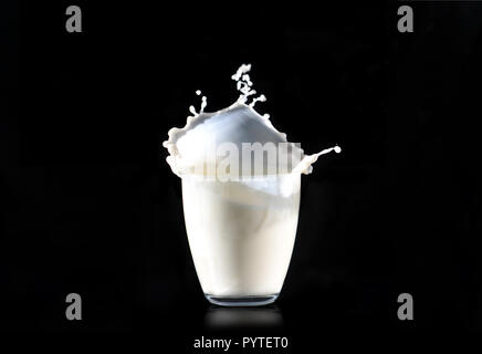 Spritzer Milch aus einem Glas transparent Glas auf einem schwarzen Hintergrund. Stockfoto