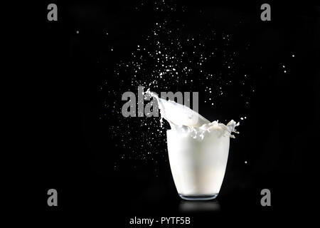 Spritzer Milch aus einem Glas transparent Glas auf einem schwarzen Hintergrund. Stockfoto