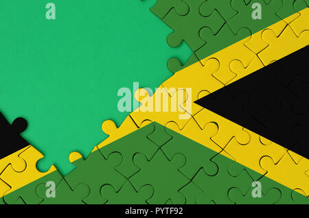 Jamaika Flagge ist auf einer abgeschlossenen Puzzle mit Freie grüne Kopie Raum auf der linken Seite dargestellt. Stockfoto