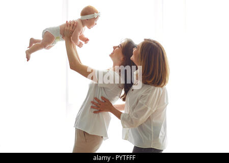 Mutter, Großmutter und Kleinkind auf Händen auf einem weißen Hintergrund. Eine Familie. Stockfoto