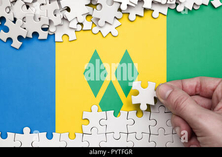 Saint Vincent und die Grenadinen ist auf einem Tisch, auf dem die menschliche Hand ein Puzzle von weißer Farbe Falten dargestellt. Stockfoto