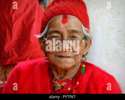 Alte nepalesische Chhetri Frau in Rot, mit einem großen Bindi auf ihrer Stirn. Stockfoto