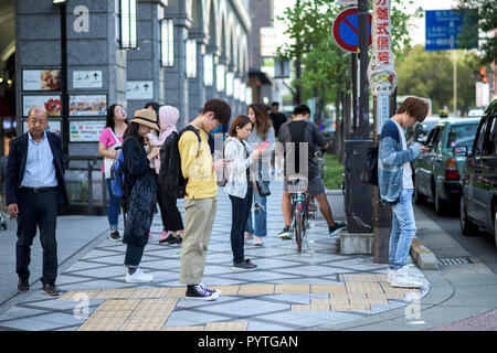 Die Menschen in den Straßen von Kyoto, einen Blick auf ihre Mobiltelefone Stockfoto