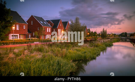 Langzeitbelichtung nacht Bild der Vorstadtstraße mit modernen ökologischen Einfamilienhäusern mit umweltfreundlichen River Bank in Veenendaal, Niederlande. Stockfoto