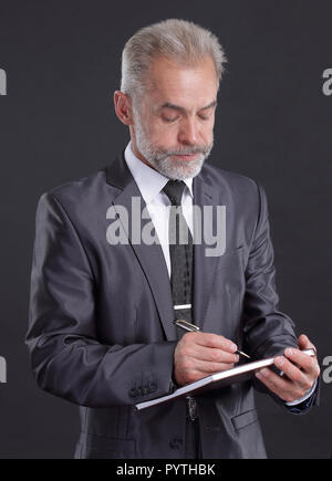 Ernsthafte Geschäftsmann unterschreibt ein Arbeitsdokument. isoliert auf Schwarz Stockfoto