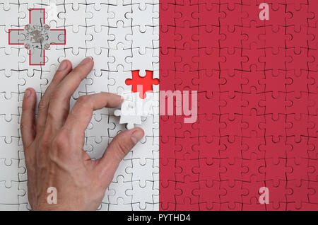 Malta Fahne wird auf ein Puzzle, die Hand des Mannes führt zu Falten dargestellt. Stockfoto