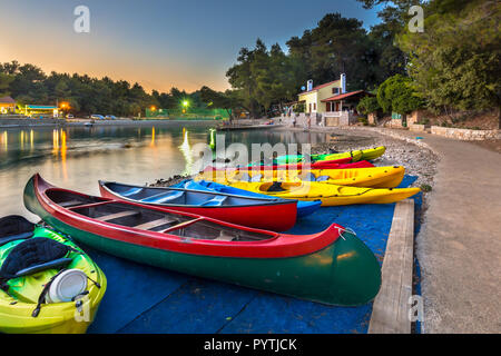 Bunte Kajaks zu mieten, in eine kroatische Bucht bei Sonnenuntergang unter wunderschön Himmel und Beleuchtung Stockfoto