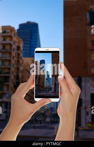 Ein Tourist ist ein Foto von der Mailänder Wolkenkratzer von der nächsten Straße in den Abend ohne Menschen auf einem Mobiltelefon Stockfoto