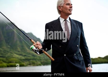 Formal ausgereift Geschäftsmann zum Fischen auf den See gekleidet. Stockfoto