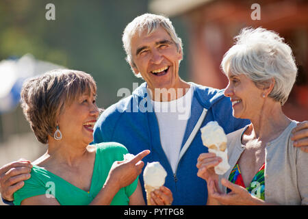 Drei lächelnd Senioren spaß essen Eis, während auf Ferien zusammen. Stockfoto