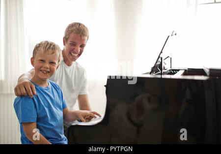 Porträt eines lächelnden Jungen und seinem älteren Bruder an einem Klavier saß. Stockfoto