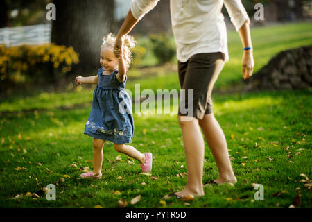 Glückliche junge Mädchen gehen Hand in Hand mit ihrer Mutter. Stockfoto