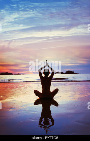 Yoga, Silhouette von Frau Meditation am Strand, vertikale Hintergrund. Stockfoto