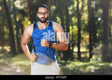 Junge athletische multikulturellen bärtigen Mann mit Brille sportish Joggen und hören seine Lieblingsmusik, gesunden Lebensstil und Personen Konzept Stockfoto