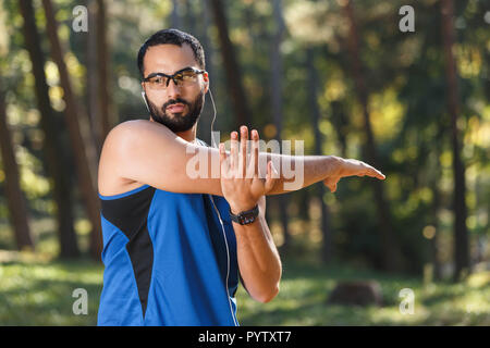 Junge athletische multikulturellen bärtigen Mann mit Brille sportish seine Lieblingsmusik hören und Tun seiner Morgengymnastik, gesunden Lebensstil und Personen Konzept Stockfoto