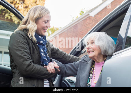 Weibliche Nachbarn geben Senior Woman A Lift im Auto Stockfoto