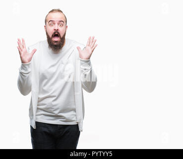 Junge kaukasier hipster Mann, Sport Kleidung über isolierte Hintergrund verrückt und erstaunt, Feiern für den Erfolg mit erhobenen Armen und offenen Augen scr Stockfoto