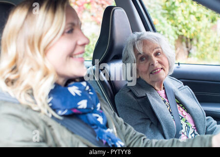 Weibliche Nachbarn geben Senior Woman A Lift im Auto Stockfoto