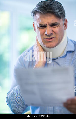 Reifer Mann Lesen Schreiben nach Erhalt die Nackenschmerzen Stockfoto