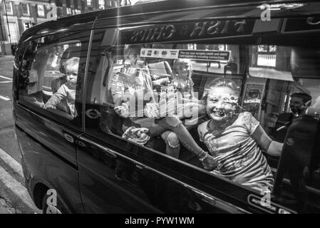 Familie im Taxi vor dem Fish and Chips Shop London. Mutter und drei Kinder im Auto, die vor der Kamera lächelten. Ein Kind sieht unglücklich aus Stockfoto