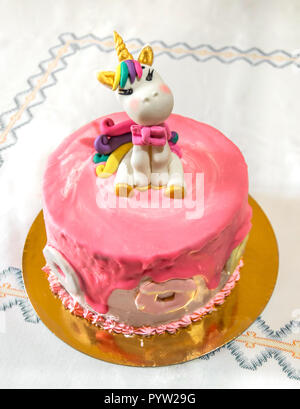 Lecker und bunte Kinder Kuchen mit einem schönen Einhorn und Dekoration. Rosa Torte mit Essbarem Abbildung eines Einhorns. Stockfoto