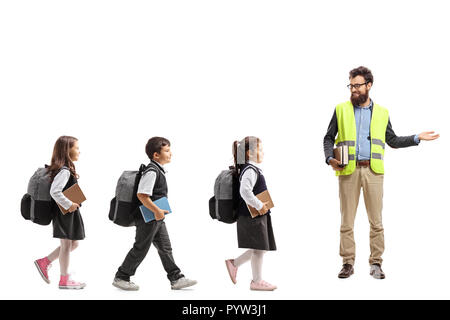 Volle Länge Profil Aufnahme von Schülern zu Fuß in einer Linie und einen Lehrer mit einer Warnweste und deutete mit der Hand auf weißem Hintergrund Stockfoto
