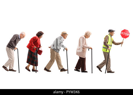 Volle Länge schoss der älteren Menschen zu Fuß in einer Zeile hinter einem älteren Mann mit einer warnweste und stop-Schild auf weißem Hintergrund Stockfoto