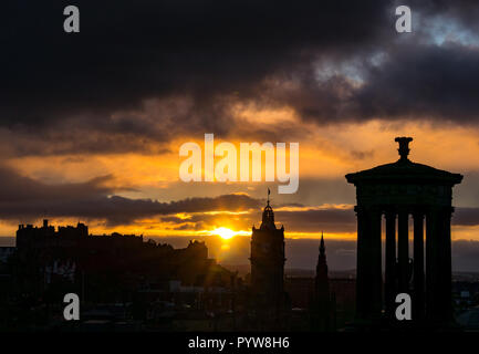 Edinburgh, Schottland, Vereinigten Königreich, 30.10.2018. UK Wetter: orange Sonnenuntergang im Zentrum der Stadt mit dem markanten Konturen von Edinburghs Bauwerke und Denkmäler einschließlich der Dugald Stewart Denkmal, Balmoral Hotel Clock Tower und das Edinburgh Castle vom Calton Hill gesehen Stockfoto