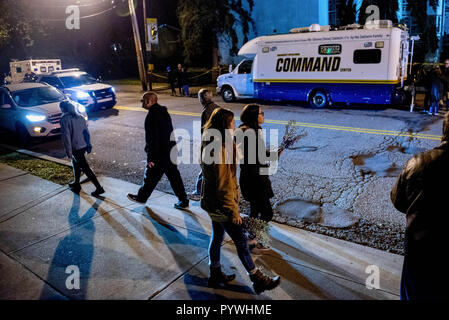 Pittsburgh, USA. 29 Okt, 2018. Frau mit Blumen überquert die Straße in die Synagoge, mit der Polizei Post-Befehl im Hintergrund. Nach der Schießerei am Baum des Lebens Synagoge in Squirrel Hill, Pittsburgh, PA, Trauer erfolgt, mit der Polizei, um die größere Gemeinschaft kommt zusammen mit Musik und Heilung. Credit: Aaron Jackendoff/SOPA Images/ZUMA Draht/Alamy leben Nachrichten Stockfoto