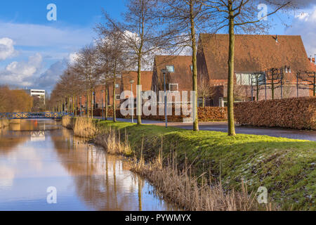 Freistehende Einfamilienhäuser entlang der Flussufer in einer ökologischen städtischen Gebiet im Winter, Groningen, Niederlande Stockfoto