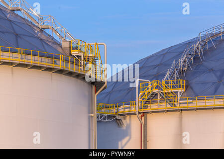 Moderne Öl Lagertanks mit Detail von Stufen und Treppen im industriellen Bereich am Hafen im warmen Abendlicht in den Niederlanden Stockfoto