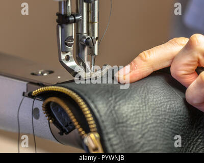 Für Industrienähmaschinen in Aktion mit den Händen arbeiten an einer Schultertasche aus Leder Stockfoto