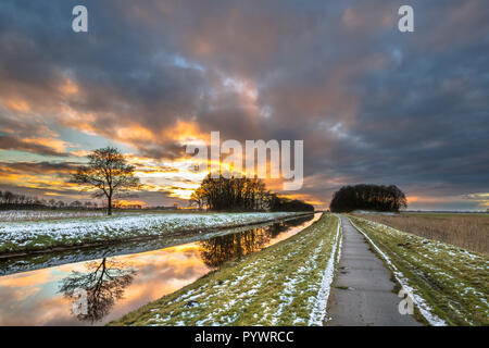 Lowland river Tjonger fließt durch flache verschneite Landschaft von Friesland in den Niederlanden Stockfoto