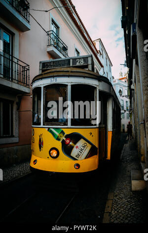 Lissabon, Portugal - 24.Oktober 2018: Traditionelle gelb elektrische Straßenbahn in einer engen Straße in Alfama, Lissabon, Portugal Stockfoto