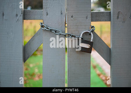 Geschlossenen Holzzaun mit kleiner Kette und Schloss aus der Nähe Außenaufnahme. keine Übertretung. Stockfoto
