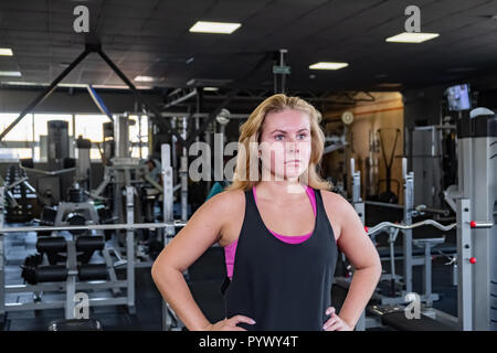 Passen junge Frau, die an der Turnhalle. Weibliche Athlet Porträt im Fitnessraum Stockfoto