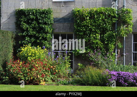 In Steinhaus umgeben von Blumen Fenster Stockfoto