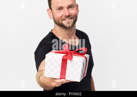 Lächelnd stattlicher Mann mit einem Geschenk Box vor weißem Hintergrund Stockfoto