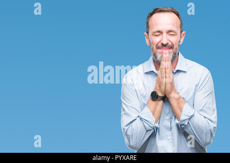 Mittleres Alter hoary Senior Business Mann über isolierte Hintergrund mit Händen gemeinsam beten um Vergebung bat lächelnd zuversichtlich. Stockfoto