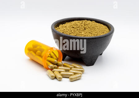 Maeng Da Kratom Pulver in schwarz Schüssel mit Kapseln von Kratom entlang Seite verschütten aus Leer orange Pille Flasche. Stockfoto