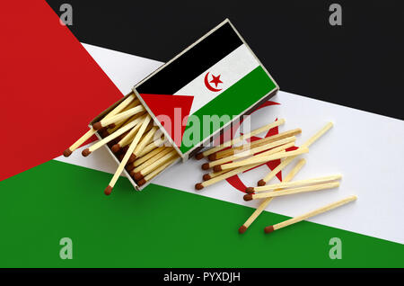 Westsahara Flagge ist auf einem offenen Streichholzschachtel, aus denen mehrere Treffer fallen gezeigt und liegt auf einer großen Fahne. Stockfoto