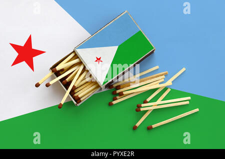 Dschibuti Flagge ist auf einem offenen Streichholzschachtel, aus denen mehrere Treffer fallen gezeigt und liegt auf einer großen Fahne. Stockfoto