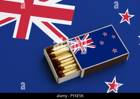 Neuseeland Flagge ist in einer offenen Streichholzschachtel, die mit Streichhölzern gefüllt ist und liegt auf einer großen Flagge gezeigt. Stockfoto