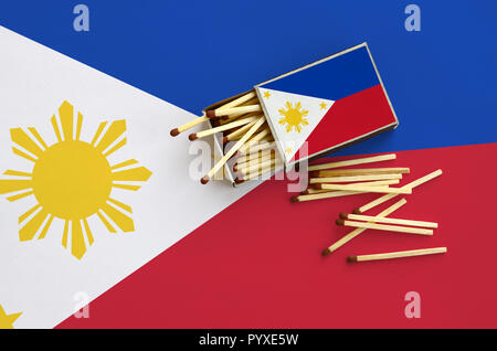 Flagge Philippinen ist auf einem offenen Streichholzschachtel, aus denen mehrere Treffer fallen gezeigt und liegt auf einer großen Fahne. Stockfoto