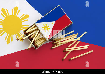 Flagge Philippinen ist auf einem offenen Streichholzschachtel, aus denen mehrere Treffer fallen gezeigt und liegt auf einer großen Fahne. Stockfoto