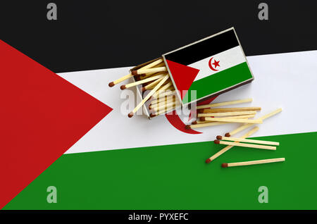 Westsahara Flagge ist auf einem offenen Streichholzschachtel, aus denen mehrere Treffer fallen gezeigt und liegt auf einer großen Fahne. Stockfoto