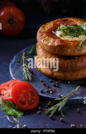 Drei hausgemachten Mini Pizza mit Tomaten, Käse und Speck, Verletzungen und Gewürzen auf hellblauem Hintergrund Vertikal Stockfoto