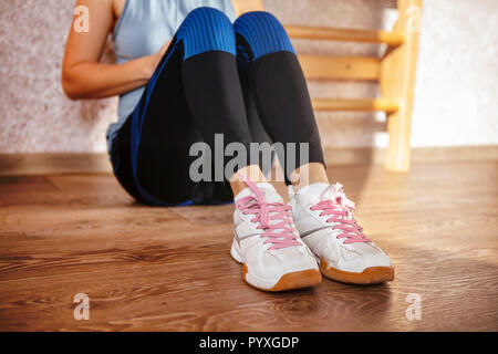Sport Schuhe von müde Mädchen, das auf einer Etage nach dem Training im Fitness Studio sitzt. Stockfoto