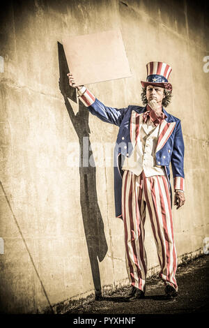 Eine unle SAM-Figur mit einem leeren Zeichen, als ob er Betteln vor. Ihre eigene Nachricht hinzufügen. Stockfoto