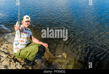 Belarus, den Fluss Pripyat. 09/12/2018: Angeln. Happy fisherman Holding große Hechte Trophäe Stockfoto